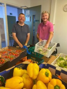 two volunteers stood behind fresh food received from fareshare