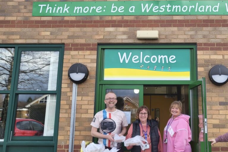 Staff from Westmorland Primary School standing outside the front door with a trolley of food.
