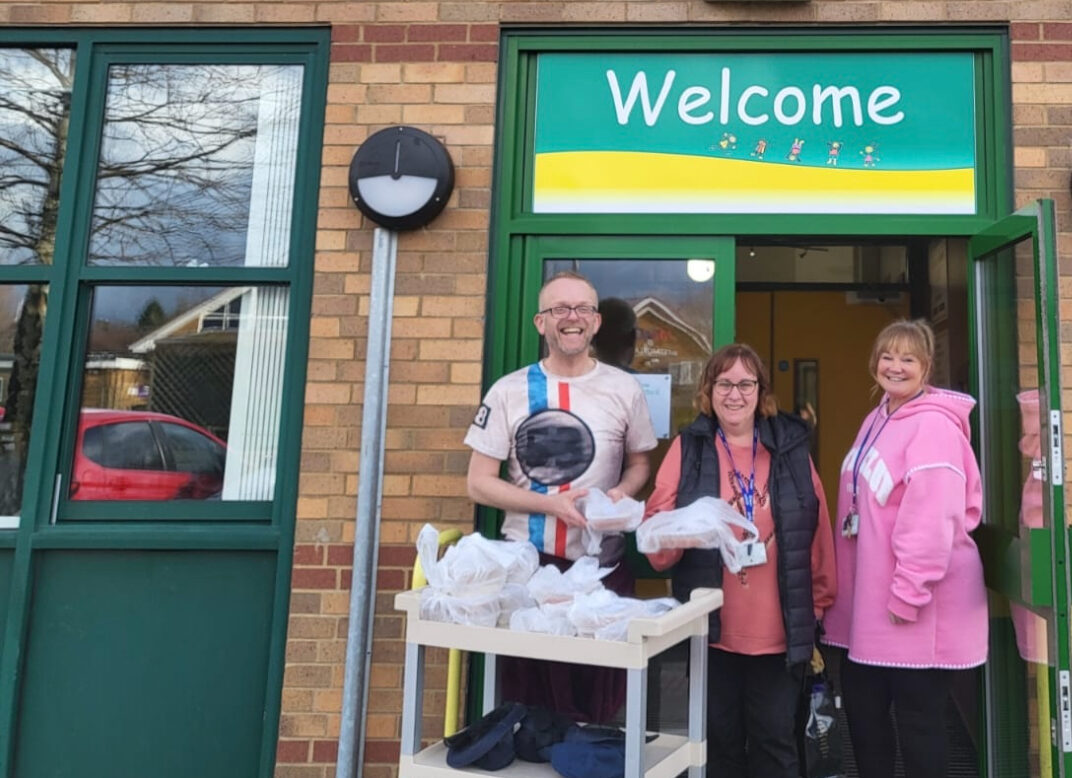 Staff from Westmorland Primary School standing outside the front door with a trolley of food.