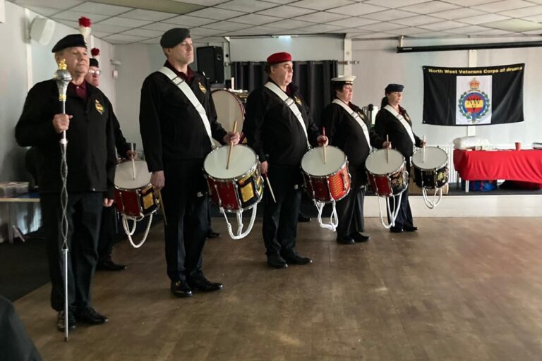 Image shows the North West Corps of Drums standing to attention at a Trafford Veterans Breakfast Club event